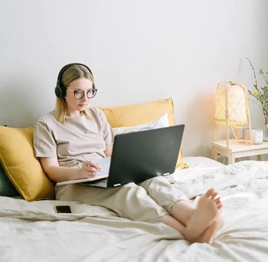 Learner practicing the Shadowing course at home with headphones and a laptop
